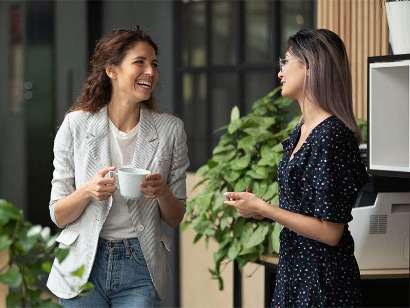 Two female employee gossiping while having coffee